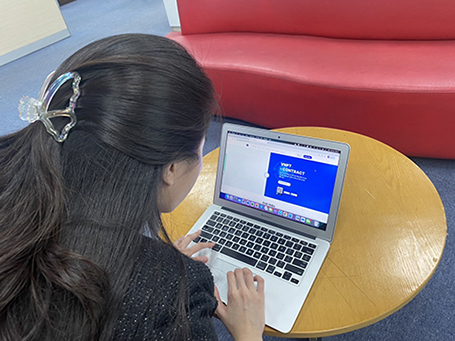 A person sitting at a table using a computer
Description automatically generated